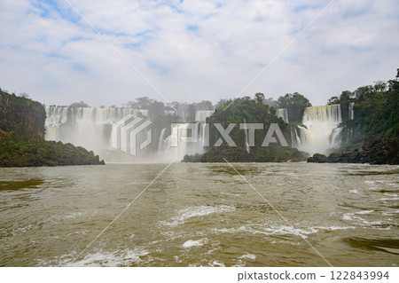 A river, waterfall in background, trees in foreground A river, waterfall in background, trees in foreground 122843994