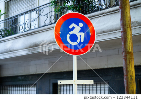 A sign with a handicapped person in a red and blue wheelchair 122844111