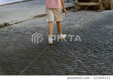 A person is leisurely walking down a charming cobblestone street A person is leisurely walking down a charming cobblestone street 122844172