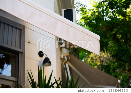 A white awning is elegantly hanging down from the side of a building A white awning is elegantly hanging down from the side of a building 122844213
