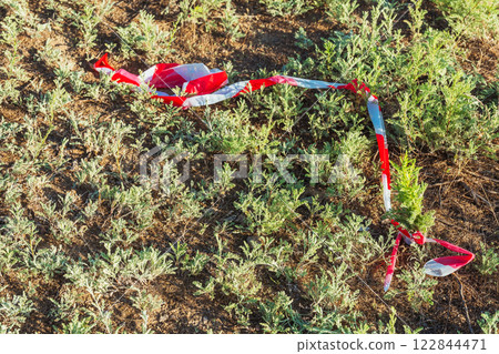 torn protective tape on grass. plastic tape with stripes torn protective tape on grass. plastic tape with stripes 122844471
