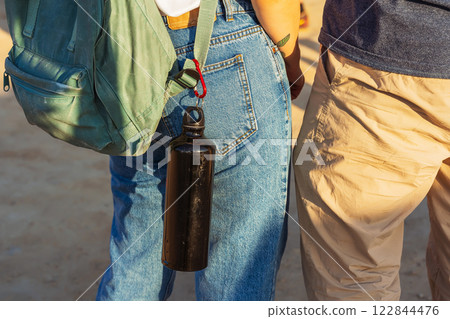 The girl has a water bottle on her belt. plastic thermos for drinking water in the steppe 122844476