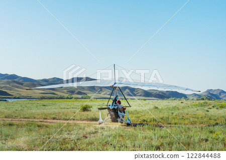 hang glider takeoff in the Kazakh steppe. light aircraft with a pilot and passenger hang glider takeoff in the Kazakh steppe. light aircraft with a pilot and passenger 122844488
