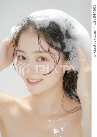Young woman shampooing her hair in the bath 122844602