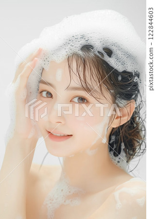 Young woman washing her hair with shampoo 122844603