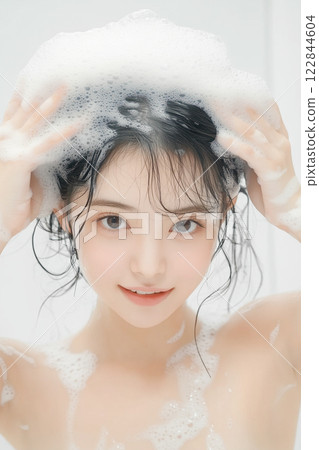 Young woman washing her hair with shampoo 122844604