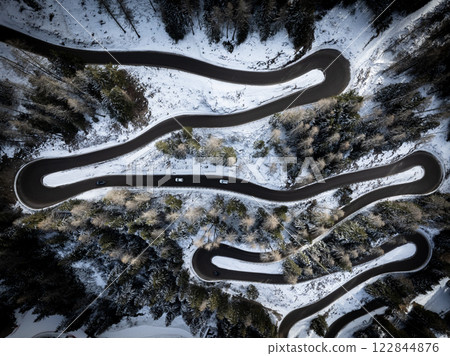 Aerial view of a car serpentine on a mountain . Road to La Thuile village and ski area . Snowy mountain serpentine in Aosta valley in Italy . 122844876
