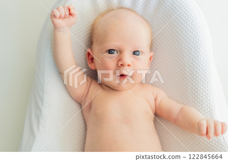 Adorable baby lying safely in a cozy infant cocoon. Comfortable and protective design for newborn care. Parenting, safety, and baby comfort concept Adorable baby lying safely in a cozy infant cocoon. Comfortable and protective design for newborn care. Parenting, safety, and baby comfort concept 122845664