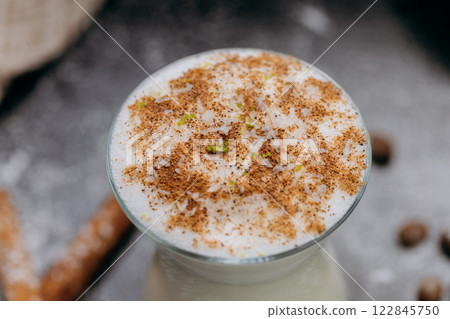 Creamy spiced milk drink in a stylish glass, topped with cinnamon and coconut flakes Creamy spiced milk drink in a stylish glass, topped with cinnamon and coconut flakes 122845750