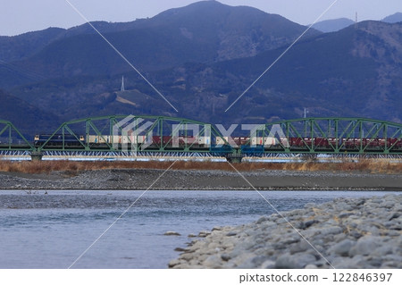 A freight train pulled by an EF65 electric locomotive crosses the Oi River with mountains lined with tea fields in the background. Photo taken on January 12, 2025. 122846397