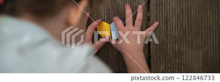Overhead view of a child making a heart shaped paper in the colors of the Ukrainian flag Overhead view of a child making a heart shaped paper in the colors of the Ukrainian flag 122846733