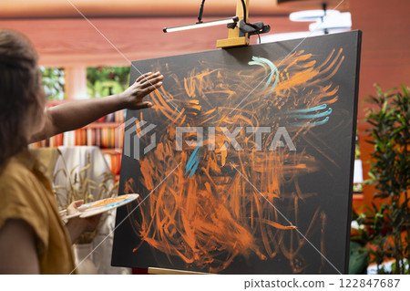 Master painter and apprentice creating a masterpiece with finger paint and handprints, using watercolor paint and mixing in on canvas. Working on an abstract artwork piece for gallery exhibition. 122847687