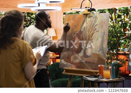 Painters team spend quality time on painting in their artistic studio, perfecting their latest masterpiece. Using multicolored pigments and innovative painting techniques to show their dedication. 122847688