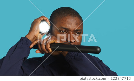 Headshot portrait of security guardian catching intruders with flashlight. Close up shot of private law enforcement employee detecting trespassers with lantern, studio backdrop, camera A Headshot portrait of security guardian catching intruders with flashlight. Close up shot of private law enforcement employee detecting trespassers with lantern, studio backdrop, camera A 122847713