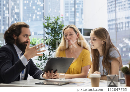 Portfolio Manager in office analyzing economic reports, developing investment objectives and communicating with clients. Financial advisor helping family wanting to save for retirement 122847765