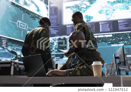 Army staff in a command post base oversees intelligence gathering activity for reconnaissance mission, live surveillance for security protocols. Military personnel helps in a defense operation. 122847812