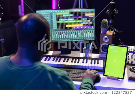 Artist producer creating new music with mix and master techniques, using a screen with copyspace layout. Skilled audio engineer editing tracks in post production, digital audio software. Artist producer creating new music with mix and master techniques, using a screen with copyspace layout. Skilled audio engineer editing tracks in post production, digital audio software. 122847827