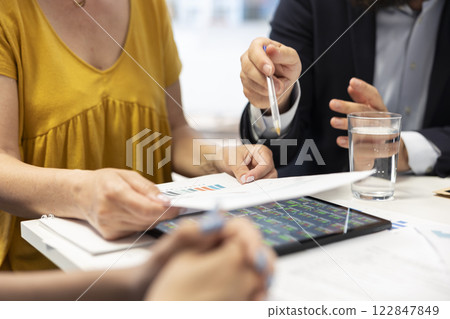 Broker meeting with customers, providing stock exchange valuation analysis to help them make money. Financial advisor looking at market shares on tablet, helping family make investments Broker meeting with customers, providing stock exchange valuation analysis to help them make money. Financial advisor looking at market shares on tablet, helping family make investments 122847849