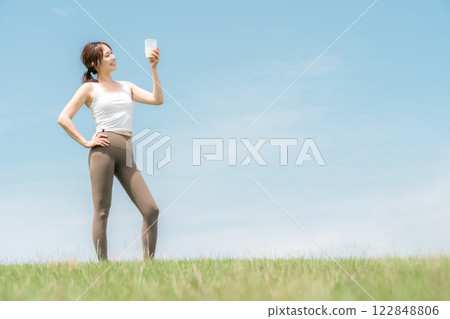 Woman drinking protein/EAA drink during exercise (blue sky) 122848806
