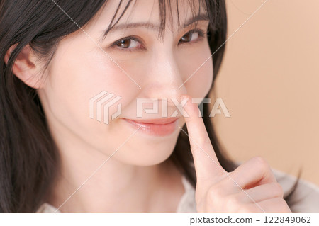 Woman pointing at the tip of her nose Woman pointing at the tip of her nose 122849062