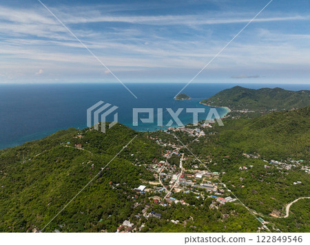 Coastal landscape with lush green hills, small islands in the distance, and a clear blue sky over turquoise waters. Koh Tao, Thailand. Coastal landscape with lush green hills, small islands in the distance, and a clear blue sky over turquoise waters. Koh Tao, Thailand. 122849546