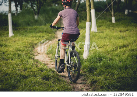Woman mountain biking on mountain trail Woman mountain biking on mountain trail 122849591