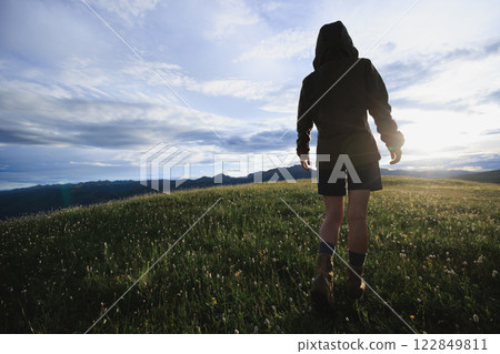 Woman hiker walking beautiful flowering grassland Woman hiker walking beautiful flowering grassland 122849811