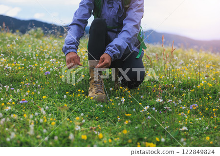 Hike tying shoelace on beautiful flowering grassland 122849824