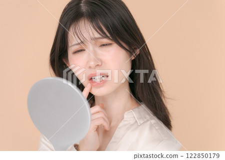 一個二十多歲的女人，一臉苦惱地看著鏡子 122850179