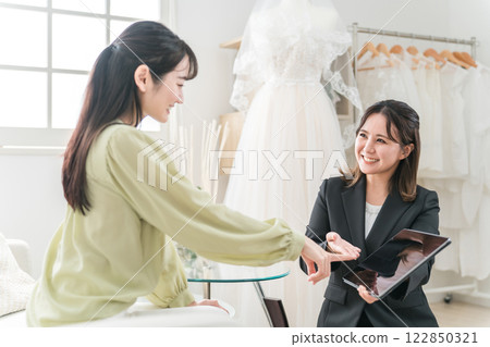 一位女士與婚禮策劃師開會選擇禮服 122850321
