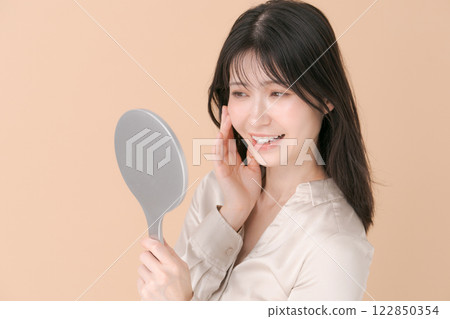 一個女人微笑著看著手鏡 一個女人微笑著看著手鏡 122850354