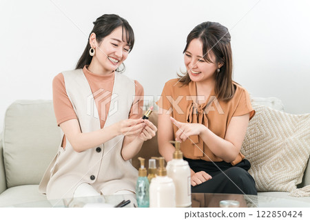Smiling Asian woman doing makeup and dressing with friends 122850424