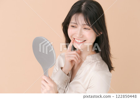 A woman looking at a mirror and smiling 122850448