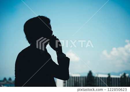 Silhouette of a businessman talking on the phone Silhouette of a businessman talking on the phone 122850623