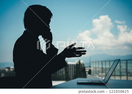 Silhouette of a businessman talking on the phone Silhouette of a businessman talking on the phone 122850625