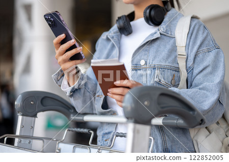 A close-up of a female traveler is waiting for her taxi at an airport pickup point. A close-up of a female traveler is waiting for her taxi at an airport pickup point. 122852005
