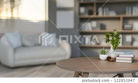 A close-up of a round wooden coffee table set in a contemporary living room. 122852047