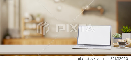 A close-up of a laptop and decorative items on a desk in a minimalist coffee shop. 122852050