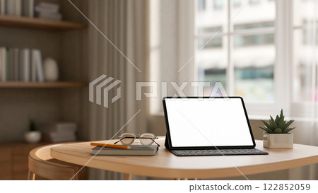 A digital tablet placed on a wooden table in a contemporary, minimalist room. 122852059