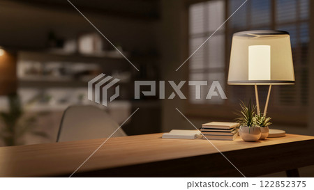 A hardwood desk with decorative items and a lamp, creating a warm atmosphere in the room at night. 122852375