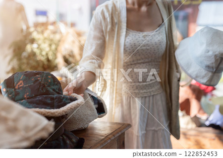 A close-up of an Asian woman carefully selecting items in a hat shop, enjoying her shopping spree. 122852453