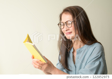 Senior woman with glasses enjoying reading 122852973