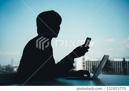 Silhouette of a man operating a smartphone (special fraud, slander) 122853770