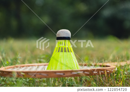 Neon yellow badminton shuttlecock and racket on green grass outdoors. Copy space soft selective focus on shuttlecocks. Alternative fitness recreational 122854720