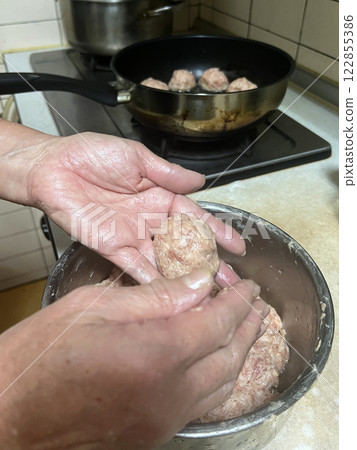 Photographing a mother shaping minced pork into round shapes and preparing to put it into the pot for cooking Photographing a mother shaping minced pork into round shapes and preparing to put it into the pot for cooking 122855386