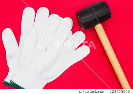 Gloves and rubber hammer on a red background 122855660