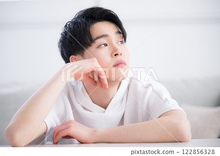 An image of beauty and beauty of a man in his 20s in a worried pose, such as thinking with his chin in his hand or resting his chin on his hand, looking up An image of beauty and beauty of a man in his 20s in a worried pose, such as thinking with his chin in his hand or resting his chin on his hand, looking up 122856328