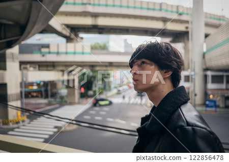 Portrait of a man wearing a black jumper walking on a footbridge 122856478