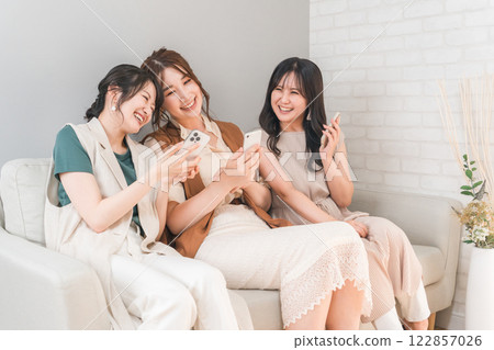 Women, friends, mom friends, and colleagues who use smartphones together at home 122857026