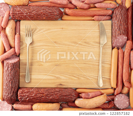 Cutting board and various dry-cured and smoked sausages. 122857182